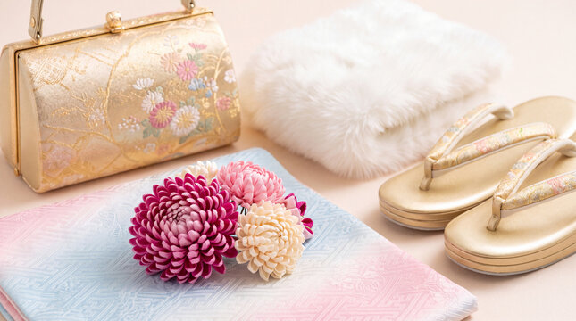 Still life of traditional Japanese accessories including a golden handbag, zori sandals, white fur stole, and colorful chrysanthemum hair ornaments.
