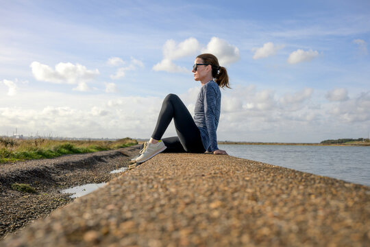 Woman in Sportswear Sitting by the Water Resting after Exercise