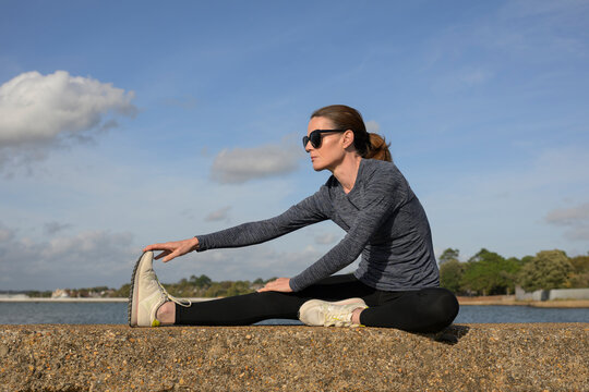 Woman Stretching on a Stone Wall by the Water