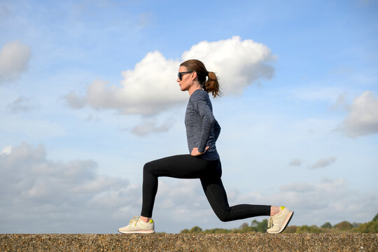 Woman Performing Lunges Outdoors on a Wall