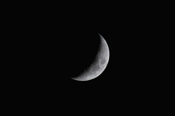 Crescent moon displaying craters and surface texture against a pitch black night sky in Bali, Taiwan. © twabian
