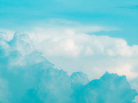 Saturated turquoise cyan sky with wispy cirrus streaks and a cumulus cloud rising from the bottom, vibrant surreal pastel sky background with copy space