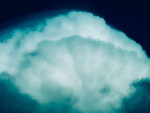Surreal teal and deep navy cumulus cloud glowing against a dark midnight blue sky, moody stylized cloudscape background with dramatic tones and copy space