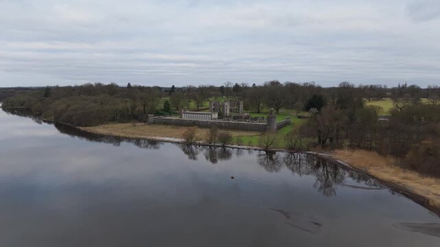 Slow aerial drift over Lough Neagh towards the ruins of Shane's Castle on the wooded lough shore, County Antrim, Northern Ireland