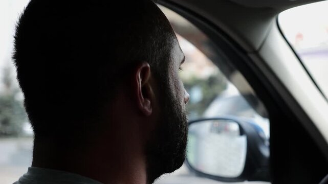 Confident bearded man looking concentrated to urban road while riding electric automobile. Guy driving the auto at highway. Serious male driver operating a motor car at town. Slow motion
