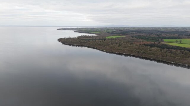 Aerial view over the calm, reflective water of Lough Neagh and the wooded shore of the Shane's Castle estate, Northern Ireland