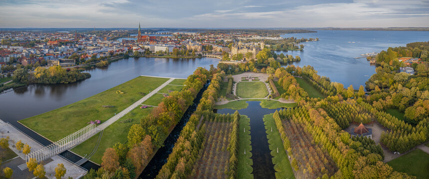 Aerial panoramic view of the city of Schwerin with historic old town skyline, cathedral, Schwerin Castle and lake landscape during autumn sunset.