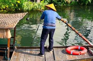 Traditional boatman rowing a wooden boat on the canal in Zhujiajiao, China © Savvapanf Photo ©