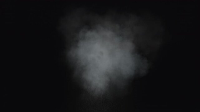 Dusty bullet impact against a wall, sending fragments of debris flying through the air. White powder burst isolated on black background. Explosive hit, scattering dust particles. Cloud of fine debris
