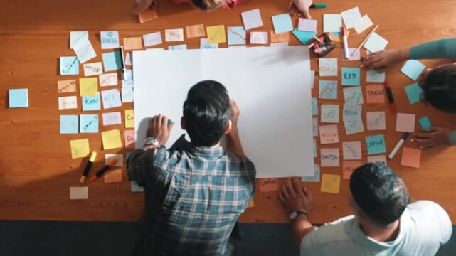 Top down view of manager writing and sharing idea by using mind map. Aerial view of smart business team working together and planning by writing in paper and drafting strategy with pencil. Symposium.