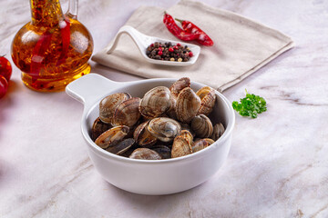 Infused olive oil and spices beside white ceramic bowl filled with fresh raw clams on marble surface seafood ingredient © Andrei Starostin