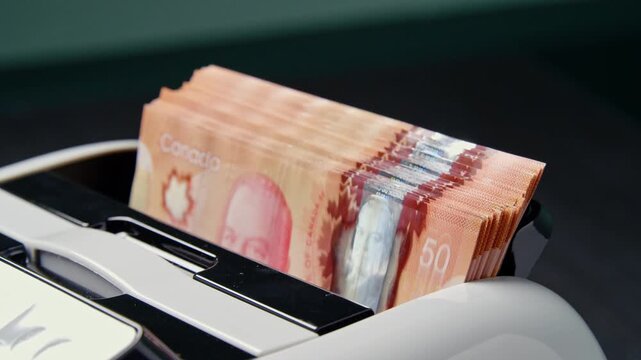 A stack of South African 50-rand notes rests inside a slot in a car dashboard, waiting to be removed and taken out