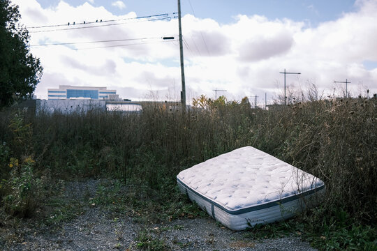 Matelat sur le d'un champs en ville. Pollution.
