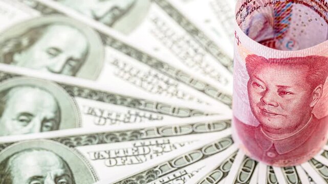 Close-up video of a rolled Chinese one hundred yuan banknote featuring Mao Zedong, surrounded by American one hundred dollar bills arranged in a circular pattern. Symbolizing economic competition betw