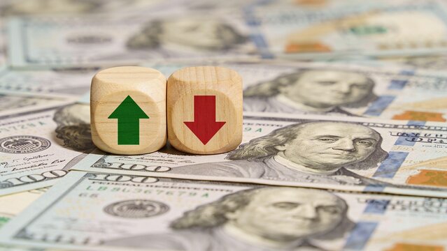 Wooden dice showing upward and downward arrows on US dollar bills background