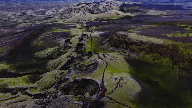 Aerial view gliding over the Lakagigar volcanic crater row with moss covered volcanic ash and rugged basalt hills across the southern highlands landscape of Iceland.