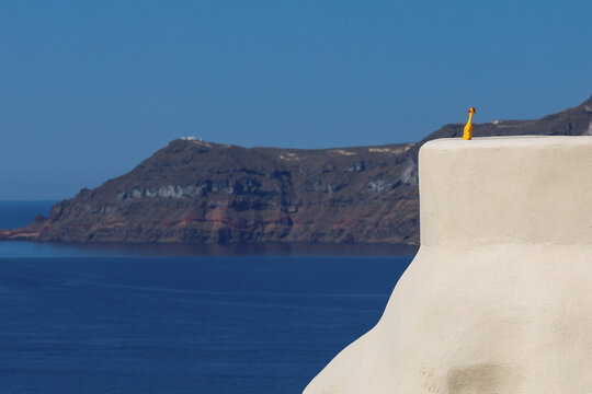Rubber chicken overlooking the Santorini caldera in Greece. Absurd comedy slapstick humor.