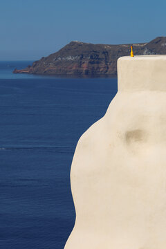 Rubber chicken overlooking the Santorini caldera in Greece. Absurd comedy slapstick humor.
