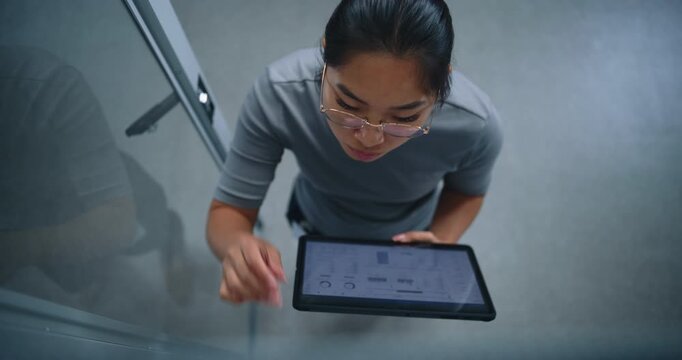 IT Specialist Performs Physical Audit of Patch Connections While Checking Network Ports Against Digital Records on Tablet. Server Room Workflow, Infrastructure Accuracy, Cable Management, Compliance.