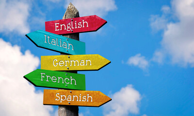 English, Italian, German, French, Spanish - wooden signpost with five arrows, sky with clouds © PX Media