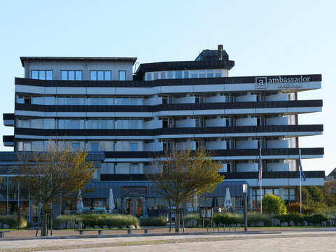 Germany, St. Peter Ording, October 17. 2026, Ambassador Hotel & Spa in Sankt Peter-Ording, showcasing a modern facade with rows of private balconies, a ground-level plaza with trees