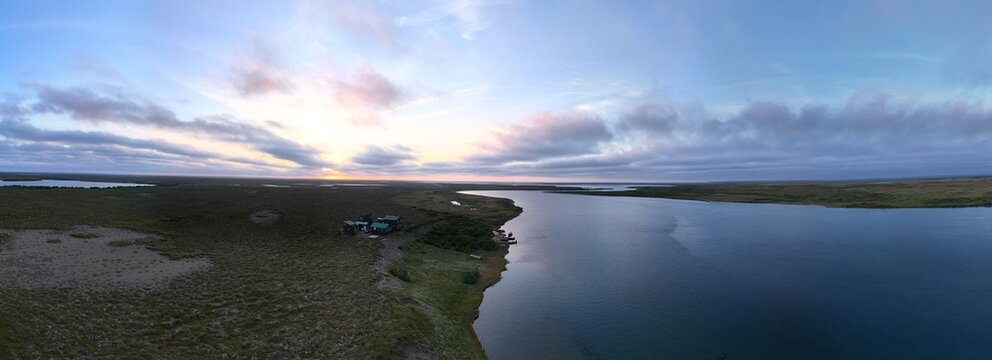 Aerial view of the Egegik river in Alaska during an evening sunset and a beautiful sky with colorful clouds as the water flows below. 