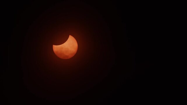 A partial solar eclipse glows a vivid orange over Nova Scotia, Canada, illuminating the skies during 2026