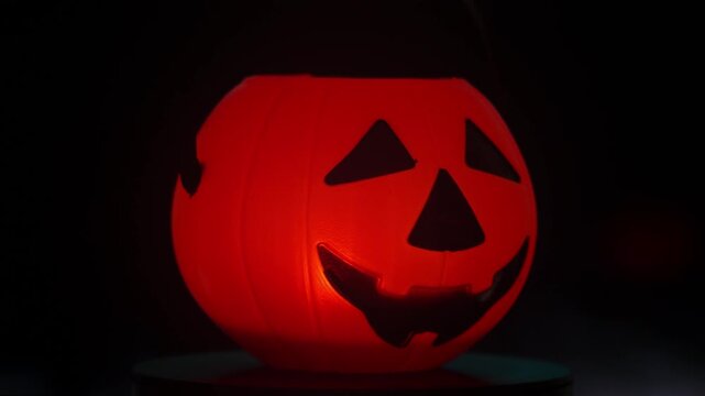 Cinematic rotating view of a lighted orange trick-or-treat pumpkin bucket surrounded by dramatic smoke effects.