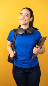Happy young latina woman standing with backpack and tablet, representing education and technology