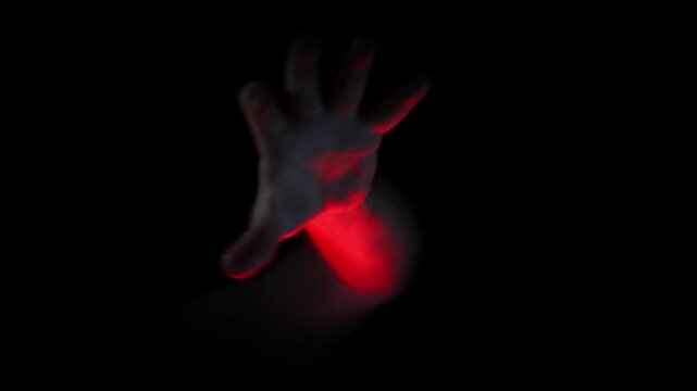 Creepy hand reaching out from pitch darkness toward the camera under dramatic red rim lighting
