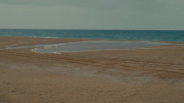 Ocean water advances across wet sand at Newport Beach as high tide reaches farther up the shore.
