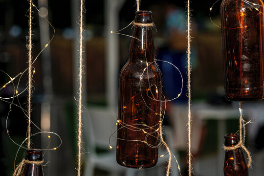 Oktoberfest celebration concept with beer bottles decorated with glowing small lights. Warm and cozy festive background for beer festival or pub party.
