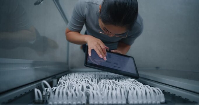 Server Room Engineer Cross Checks NMS Dashboard With Physical Patch Cable Connections. Professional Workflow, Digital Infrastructure Monitoring, Port Verification and Network Configuration Control.