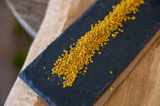 Bee pollen granules on dark slate plate for natural health supplements
