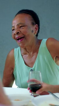 Senior woman of African descent smiling and nodding during friendly family chat at table