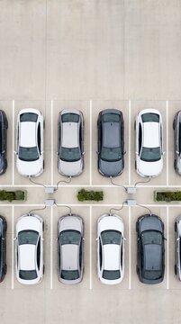 Aerial view of electric cars charging in a row of parking bays with cables connected to stations