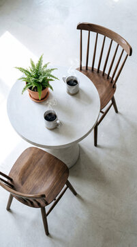Overhead view of two steaming coffee mugs and empty wooden chairs, waiting and companionship concept