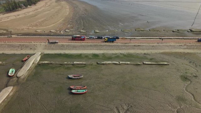 Fishing Boats Stranded on Tidal Mudflat Beside Coastal Road