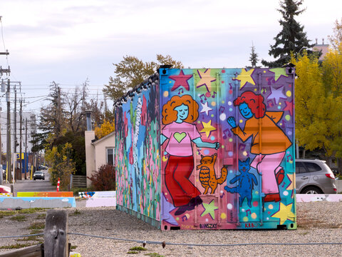 Calgary, AB, Canada. Oct 17, 2026. Side view of a colourful painted shipping container with street art mural of dancing figures and cats.