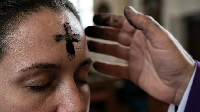 Close-Up of Ash Being Applied in the Shape of a Cross to a Person's Forehead on Ash Wednesday, Christian Lenten Ritual Symbolizing Repentance, Mortality, Faith, Humility, Prayer and Spiritual Renewal