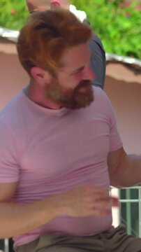 Elderly father joyfully engaging in playful dance with adult son during outdoor barbecue celebration