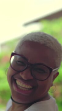Expressive Afro-Latina woman with glasses dancing excitedly and celebrating life outdoors against natural background