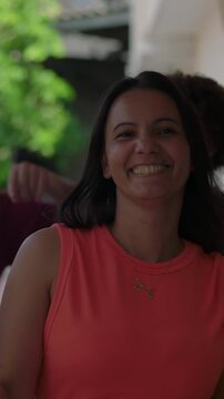 Joyful Hispanic woman waving and dancing in front of diverse friends on porch