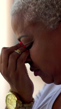 Overwhelmed African American woman pinching bridge of nose, feeling headache