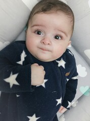 Adorable baby boy lying in bed wearing star pattern blue fleece onesie © Irem