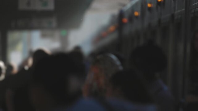 Passengers board a commuter train at a railway platform during the evening rush hour