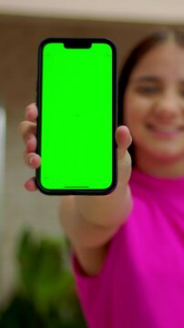Adolescent girl holding smartphone with green screen close up outdoors, mobile advertising mockup