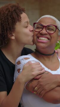 African American mother and teenage son smiling and embracing outdoors, family affection