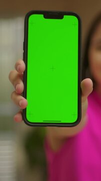 Close up hand holding vertical smartphone green screen, mobile app mockup outdoors