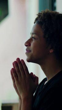 Devout Hispanic boy of African descent praying outdoors with eyes closed in peace